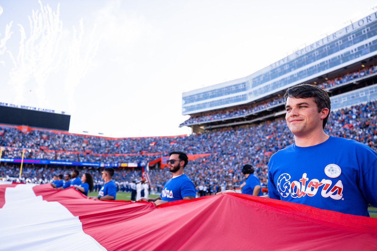 Veterans hold the edges of the American flag on the field at Ben Hill Griffin Stadium.