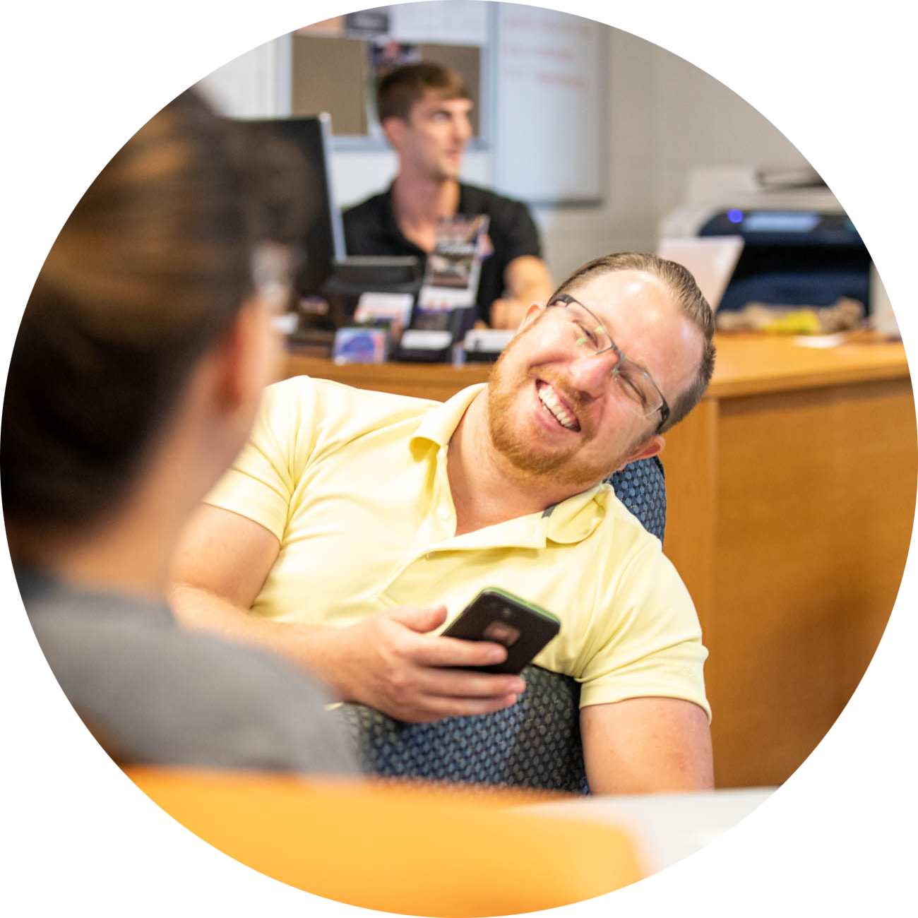 Two veterans have a conversation at the Veteran's Success Center. A UF staff member sits at a support desk in the background.